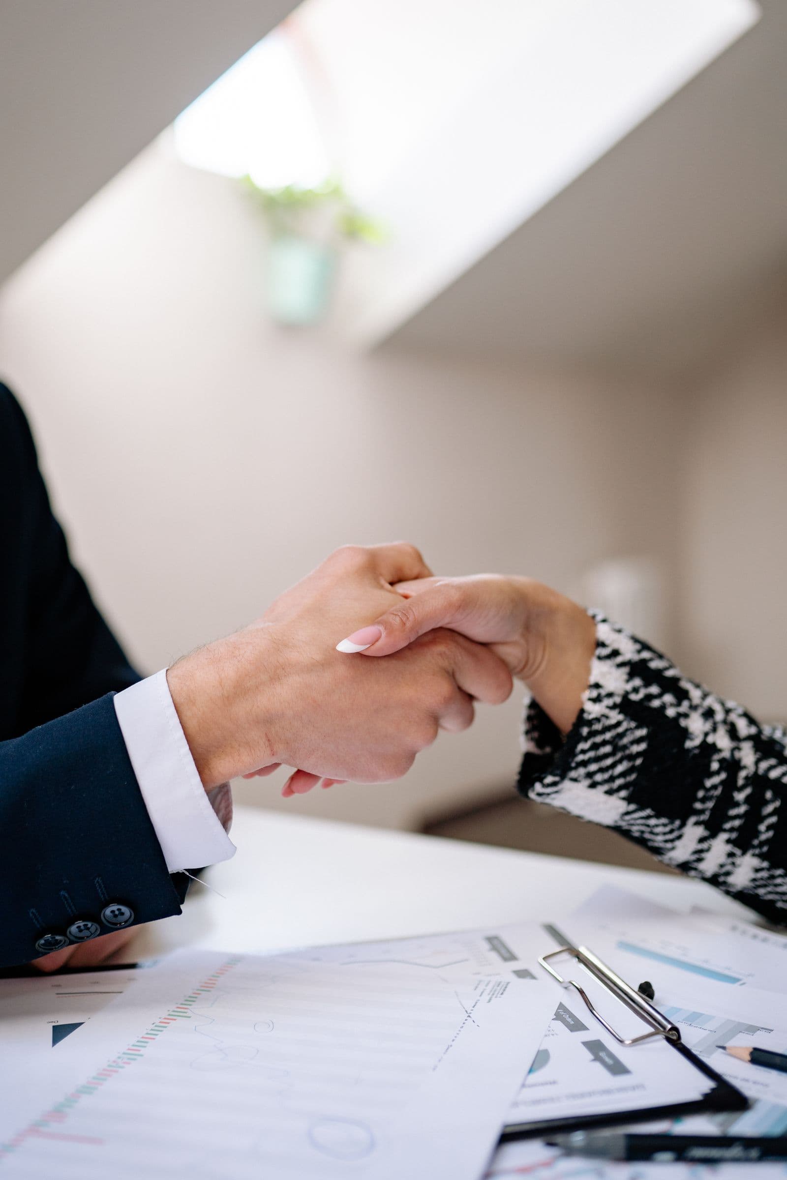 Poignée de main entre deux professionnels autour de documents de travail
